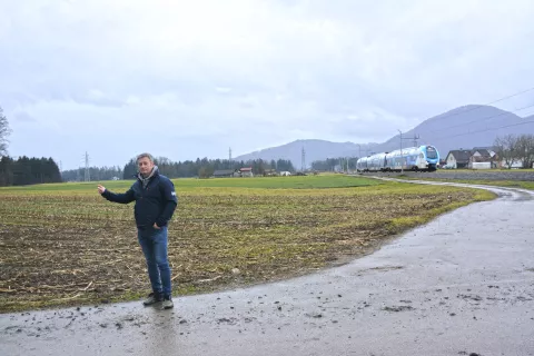 Matjaž Krajnik opozarja, da ima trasa, ki jo načrtuje država, škodljive vplive na okolje in ljudi. Na Godešič (na sliki) naj bi nova dvotirna železnica prišla iz Sorškega polja in se obstoječi priključila na koncu vasi. / Foto: Maja Bertoncelj