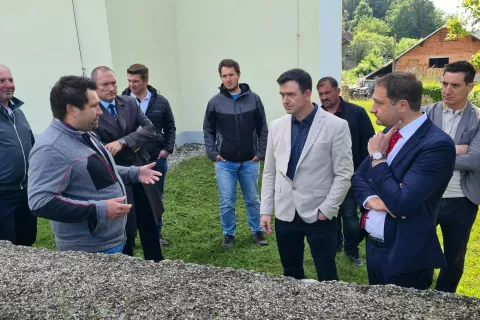 Kmet Metod Jagodic (v ospredju levo) je evropskemu komisarju Christophu Hansenu (v ospredju desno) predstavil kmetijo in pokazal pašnik v bližini cerkve. / Foto: Cveto Zaplotnik