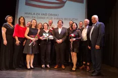 Organizatorji večera, zborovodje in gostje na odru kulturnega doma Slovenskega prosvetnega društva Srce. V sredini predsednica društva Gitti Neuwersch in župan Dobrel vasi Wolfgang Stefitz. / Foto: Jože Košnjek