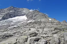 Zadnji metri pred vrhom Rifenkopf, ki ga označuje leseni križ. Mogočna gora v ozadju je ledeni&scaron;ki Olperer. / Foto: Jelena Justin