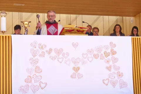 Pater dr. Robert Bahčič ke v nedeljo blagoslovil nov kelih in klekljane oltarne prte z všitimi srci. / Foto: – Foto: Romarski Urad Brezje