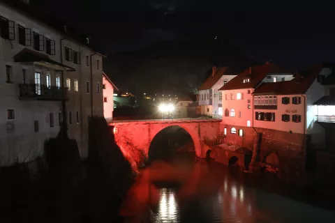 Kamniti most ob Dnevih Škofjeloškega pasijona žari v pasijonsko rdeči barvi. / Foto: Gorazd Kavčič