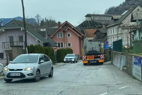 Težki tovornjaki z nekaj ton težkimi ploščami so do obrata podjetja SIJ Acroni prisiljeni voziti po ozki cesti skozi vas. Ob cesti poteka tudi šolska pot.