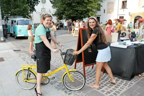 Iz vinoteke Sodček je na stojnico na Linhartovem trgu v četrtek zvečer ponudba prispela kar s kolesom ... / Foto: 